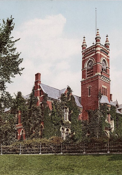 A photochrom postcard of Smith College, a side view of a red brick building with tall green trees in front