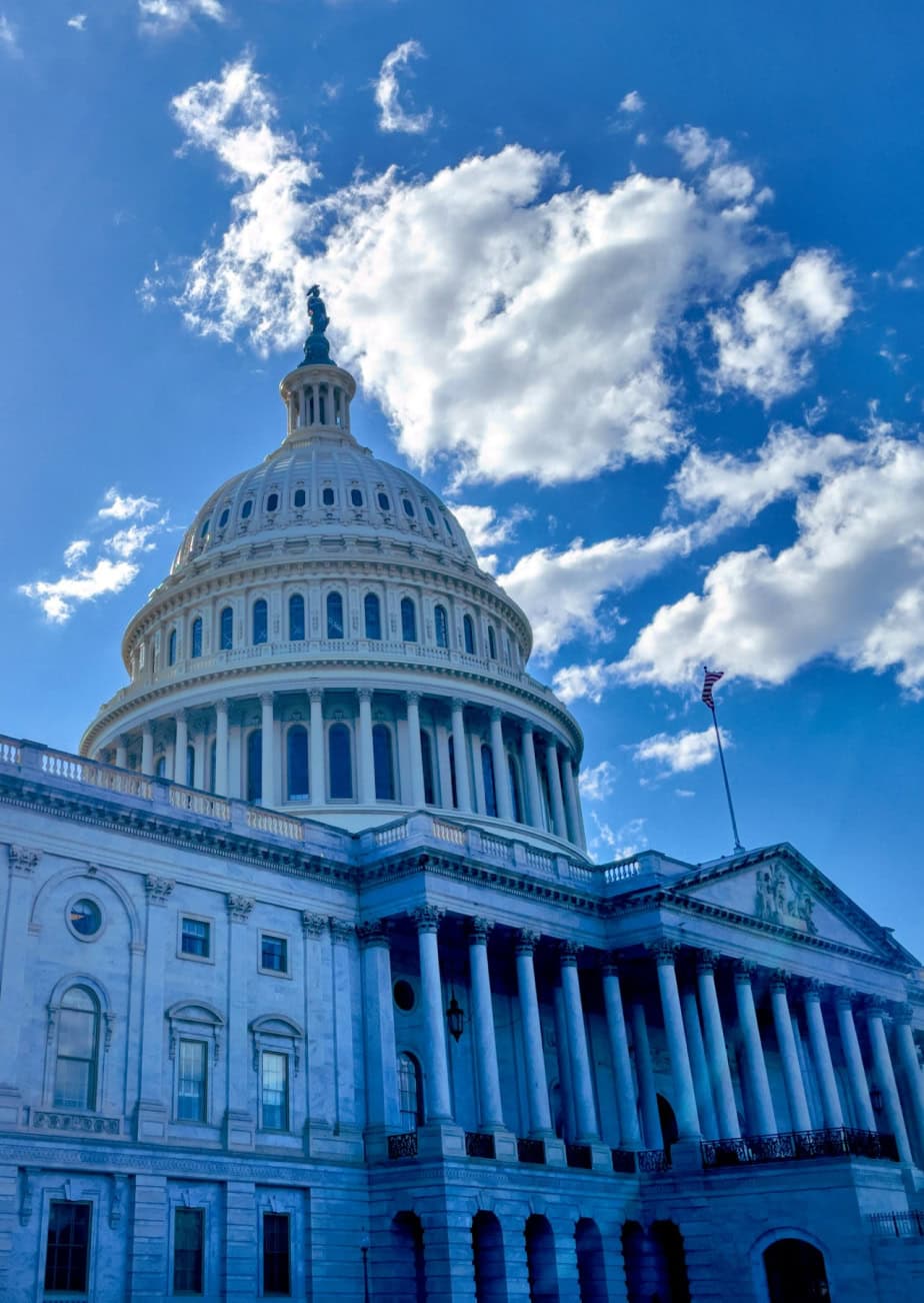 The US Capitol building against a blue sky and clouds