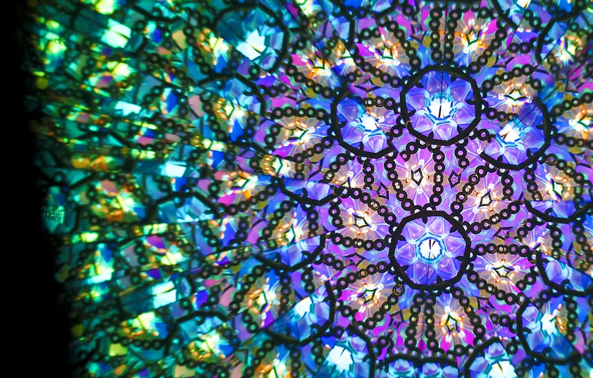 Inside of a kaleidoscope, with purple, pink, blue, and green colors.